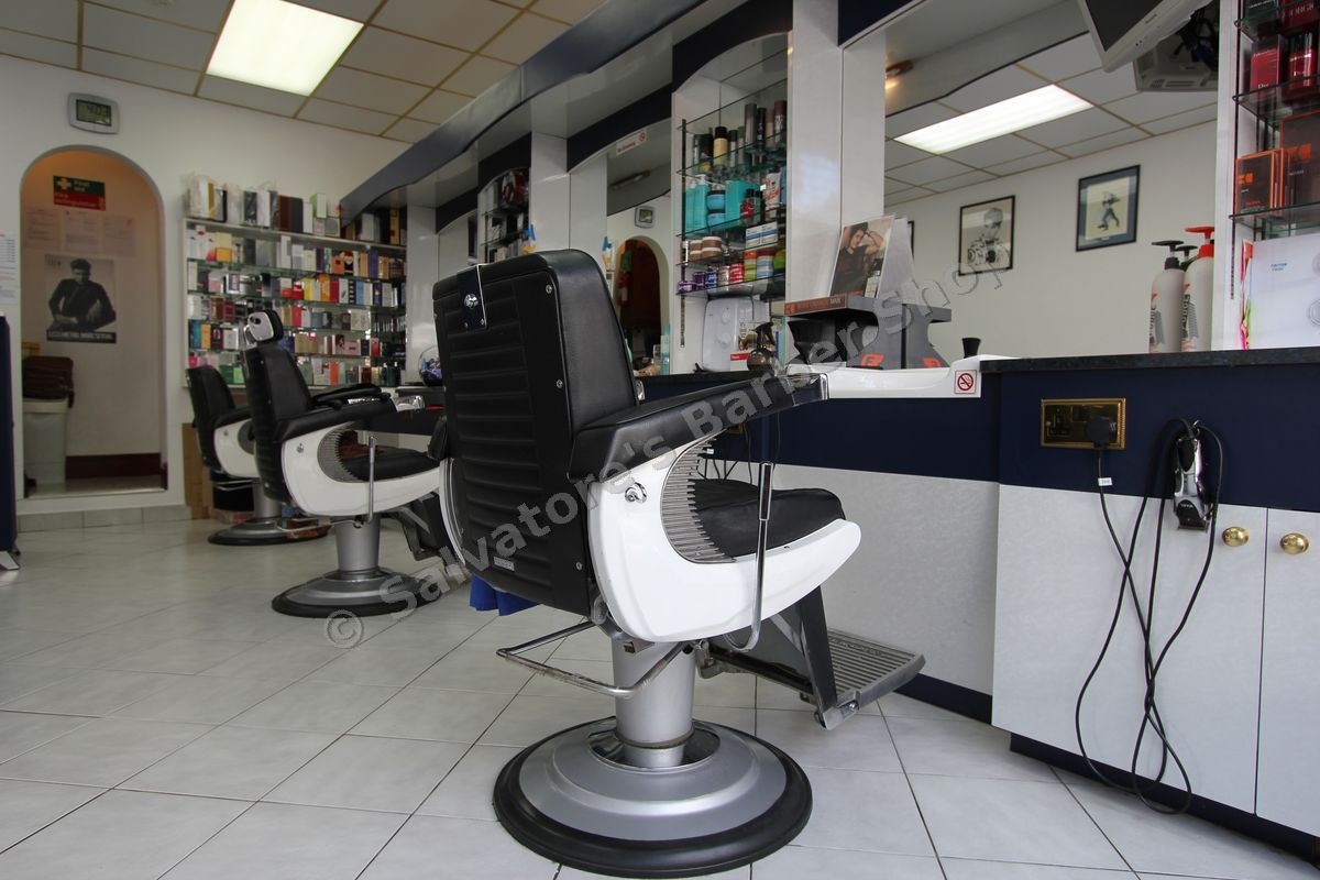Inside Salvatore's: three black and white barber chairs, mirrors and shelves of grooming products